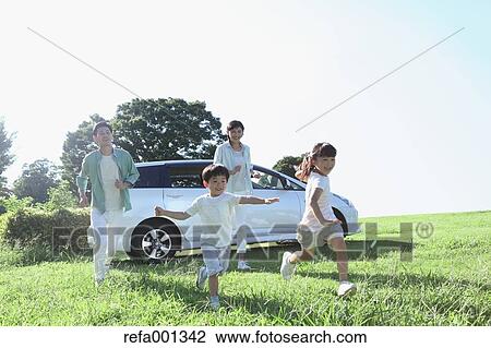 Stock Image - Happy Japanese family with car in a city park. Fotosearch
