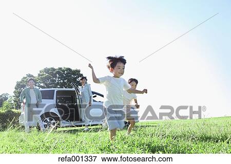 Stock Photo - Happy Japanese family with car in a city park. Fotosearch