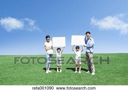 Stock Image - Happy Japanese family with whiteboards in a city park. Fotosearch