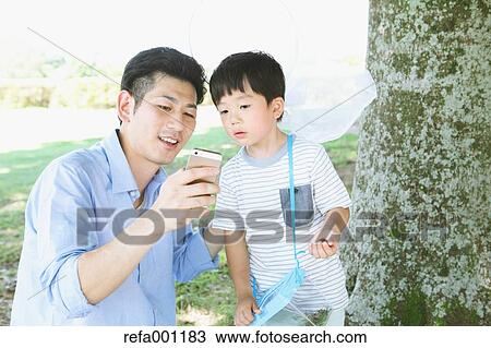 Happy Japanese father and son catching insects in a city park View Large Photo Image Stock Image - Happy Japanese father and son catching insects in a city park. Fotosearch