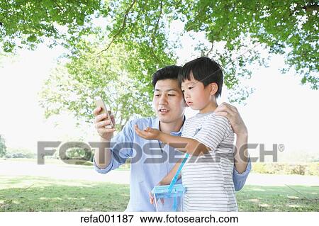 Happy Japanese father and son catching insects in a city park View Large Photo Image Stock Photo - Happy Japanese father and son catching insects in a city park. Fotosearch