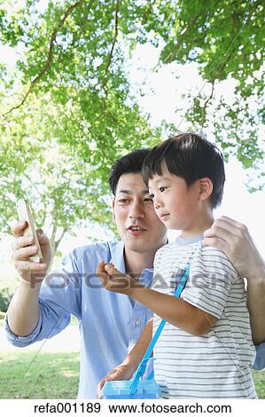 Happy Japanese father and son catching insects in a city park View Large Photo Image Stock Photo - Happy Japanese father and son catching insects in a city park. Fotosearch
