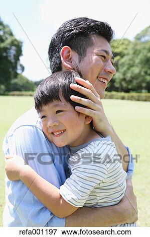 Happy Japanese father and son hugging in a city park View Large Photo Image Stock Photo - Happy Japanese father and son hugging in a city park. Fotosearch