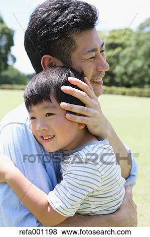 Happy Japanese father and son hugging in a city park View Large Photo Image Stock Photo - Happy Japanese father and son hugging in a city park. Fotosearch