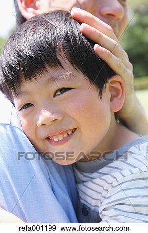Happy Japanese father and son hugging in a city park View Large Photo Image Stock Photo - Happy Japanese father and son hugging in a city park. Fotosearch