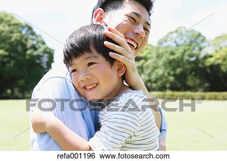 Happy Japanese father and son hugging in a city park View Large Photo Image Stock Photograph - Happy Japanese father and son hugging in a city park. Fotosearch