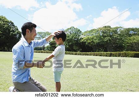 Stock Image - Happy Japanese father and son in a city park. Fotosearch