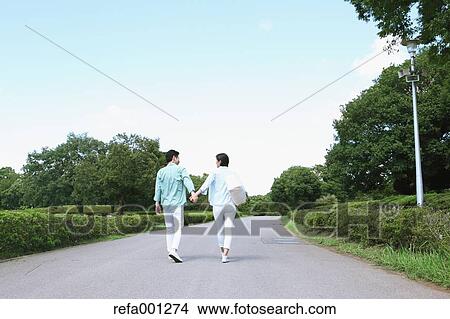 Picture - Japanese couple walking in a city park. Fotosearch