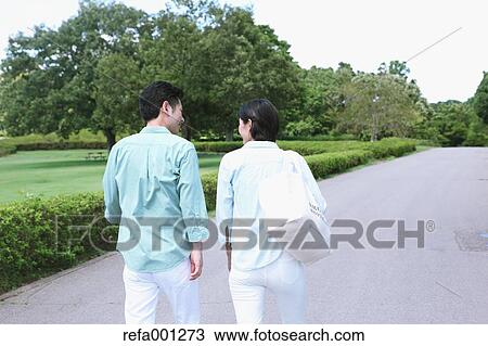 Stock Image - Japanese couple walking in a city park. Fotosearch