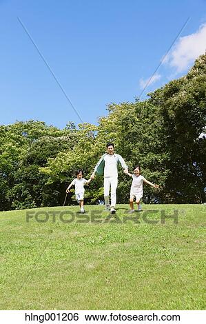 Stock Photograph - Japanese father playing with his kids in a city park. Fotosearch