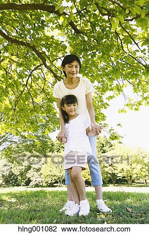 Stock Image - Japanese mother and daughter in a city park. Fotosearch