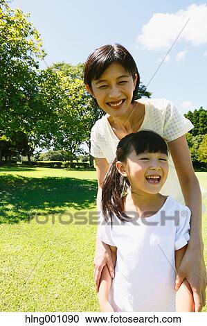 Stock Image - Japanese mother and daughter in a city park. Fotosearch