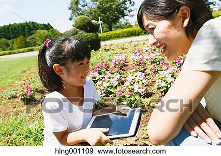 Japanese mother and daughter with tablet in a city park View Large Photo Image Stock Photo - Japanese mother and daughter with tablet in a city park. Fotosearch
