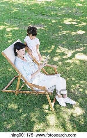 Stock Photo - Japanese mother and daughter with tablet in a city park. Fotosearch