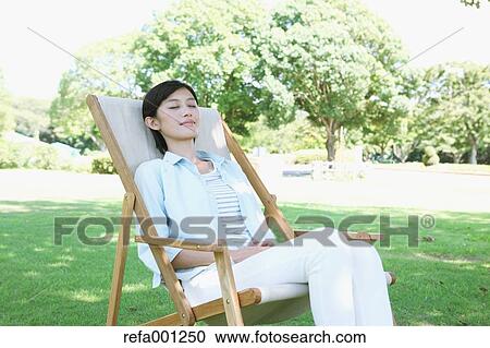 Japanese woman resting on deck chair in a city park View Large Photo Image Stock Image - Japanese woman resting on deck chair in a city park. Fotosearch