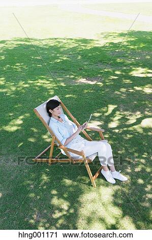 Japanese woman with tablet on deck chair in a city park View Large Photo Image Stock Image - Japanese woman with tablet on deck chair in a city park. Fotosearch