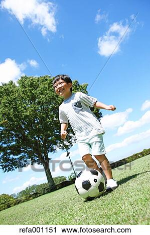 Japanese young boy playing soccer in a city park View Large Photo Image Stock Image - Japanese young boy playing soccer in a city park. Fotosearch