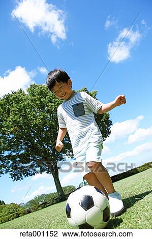 Japanese young boy playing soccer in a city park View Large Photo Image Stock Image - Japanese young boy playing soccer in a city park. Fotosearch