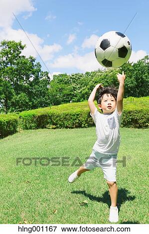 Japanese young boy playing soccer in a city park View Large Photo Image Stock Photo - Japanese young boy playing soccer in a city park. Fotosearch