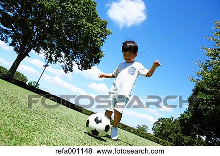 Japanese young boy playing soccer in a city park View Large Photo Image Stock Photo - Japanese young boy playing soccer in a city park. Fotosearch