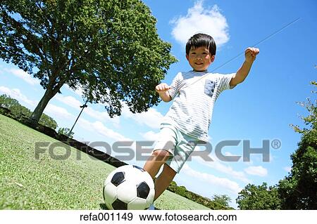 Japanese young boy playing soccer in a city park View Large Photo Image Stock Photo - Japanese young boy playing soccer in a city park. Fotosearch
