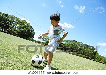 Japanese young boy playing soccer in a city park View Large Photo Image Stock Photo - Japanese young boy playing soccer in a city park. Fotosearch
