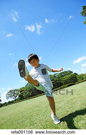 Stock Photo - Japanese young boy playing soccer in a city park. Fotosearch