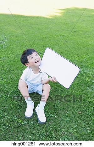 Stock Image - Japanese young boy with whiteboard in a city park. Fotosearch