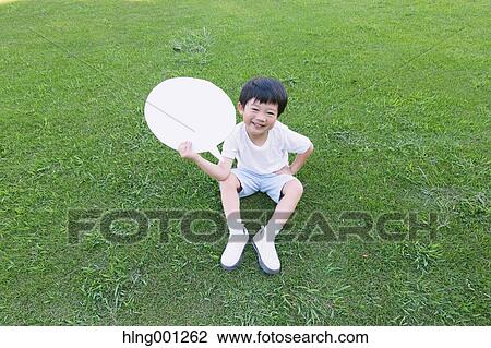 Stock Image - Japanese young boy with whiteboard in a city park. Fotosearch