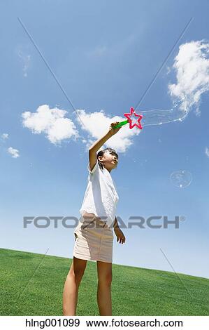 Japanese young girl playing with soap bubbles in a city park View Large Photo Image Stock Photo - Japanese young girl playing with soap bubbles in a city park. Fotosearch