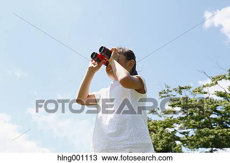 Stock Image - Japanese young girl with binoculars in a city park. Fotosearch