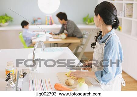 Mother cooking in an open kitchen watching father and son doing homework at the dining table View Large Photo Image Stock Image - Mother cooking in an open kitchen watching father and son doing homework at the dining table. Fotosearch