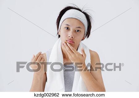 Stock Image - Portrait of young man doing skin care. Fotosearch