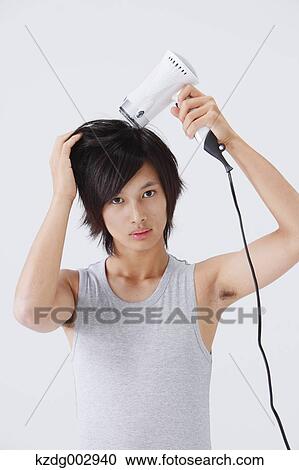 Portrait of young man drying his hair View Large Photo Image Stock Image - Portrait of young man drying his hair. Fotosearch
