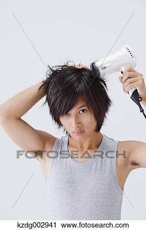 Stock Image - Portrait of young man drying his hair. Fotosearch