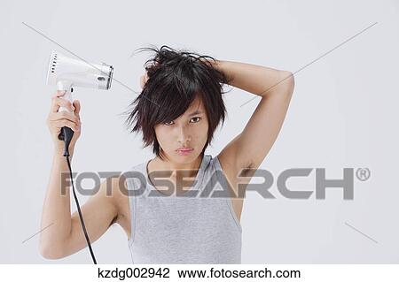 Portrait of young man drying his hair View Large Photo Image Stock Image - Portrait of young man drying his hair. Fotosearch