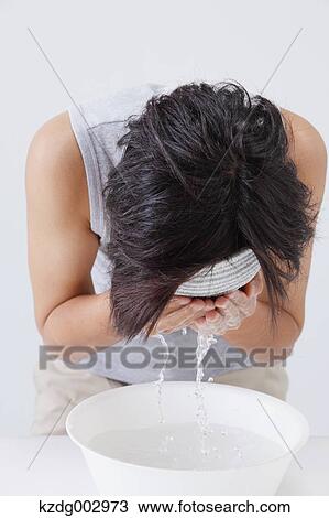 Stock Image - Portrait of young man washing his face. Fotosearch