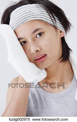 Stock Photography - Portrait of young man wiping his face. Fotosearch