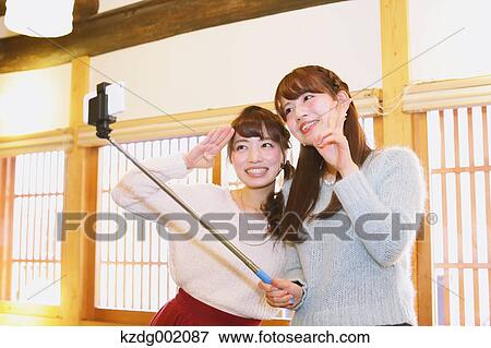 Stock Photo - "Two young Japanese women taking a selfie in Kawagoe old town, Japan". Fotosearch