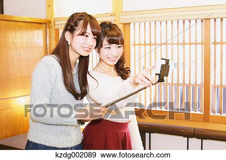 Stock Photo - "Two young Japanese women taking a selfie in Kawagoe old town, Japan". Fotosearch