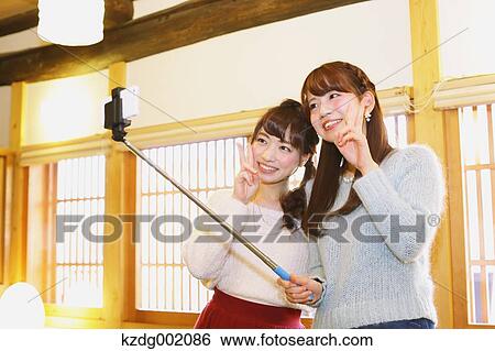 Stock Photograph - "Two young Japanese women taking a selfie in Kawagoe old town, Japan". Fotosearch