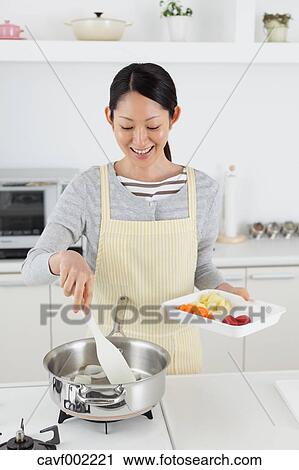 Stock Image - Woman cooking in an open kitchen. Fotosearch