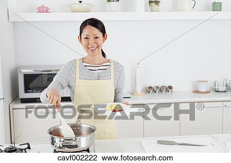 Stock Image - Woman cooking in an open kitchen. Fotosearch