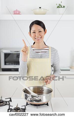 Stock Photo - Woman cooking in an open kitchen. Fotosearch