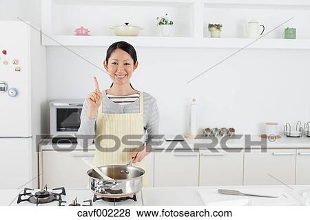 Woman cooking in an open kitchen View Large Photo Image Stock Photo - Woman cooking in an open kitchen. Fotosearch