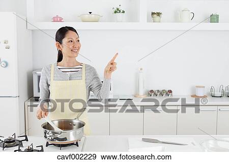 Woman cooking in an open kitchen View Large Photo Image Stock Photo - Woman cooking in an open kitchen. Fotosearch