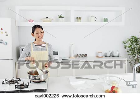 Woman cooking in an open kitchen View Large Photo Image Stock Photograph - Woman cooking in an open kitchen. Fotosearch
