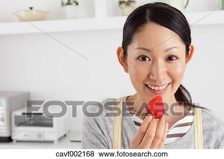 Woman eating strawberry in an open kitchen View Large Photo Image Stock Photo - Woman eating strawberry in an open kitchen. Fotosearch