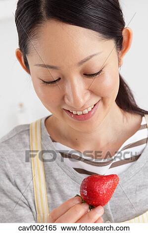 Woman eating strawberry in an open kitchen View Large Photo Image Stock Photography - Woman eating strawberry in an open kitchen. Fotosearch