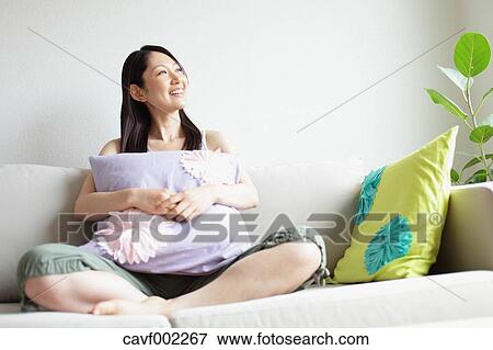 Woman holding a pillow and relaxing on the sofa View Large Photo Image Stock Photo - Woman holding a pillow and relaxing on the sofa. Fotosearch
